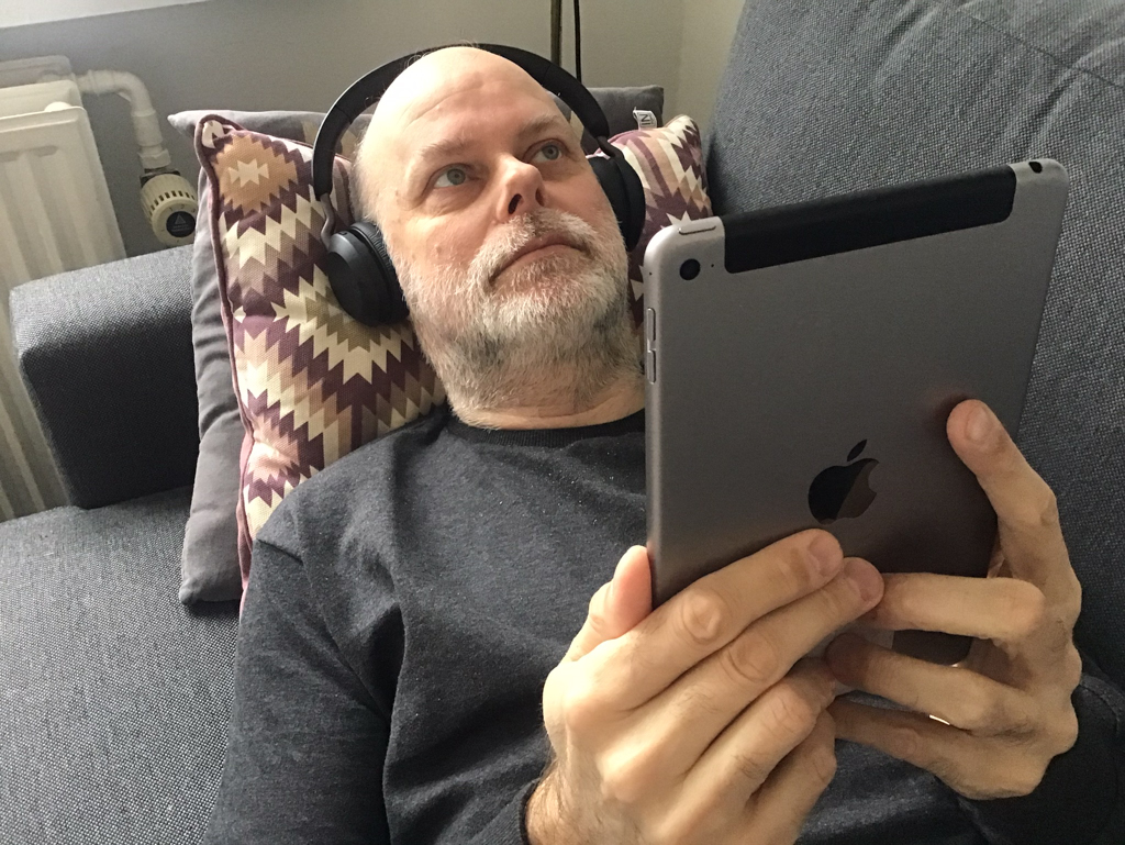 Kristian Marcussen liggende på sofa med iPad og hovedtelefoner